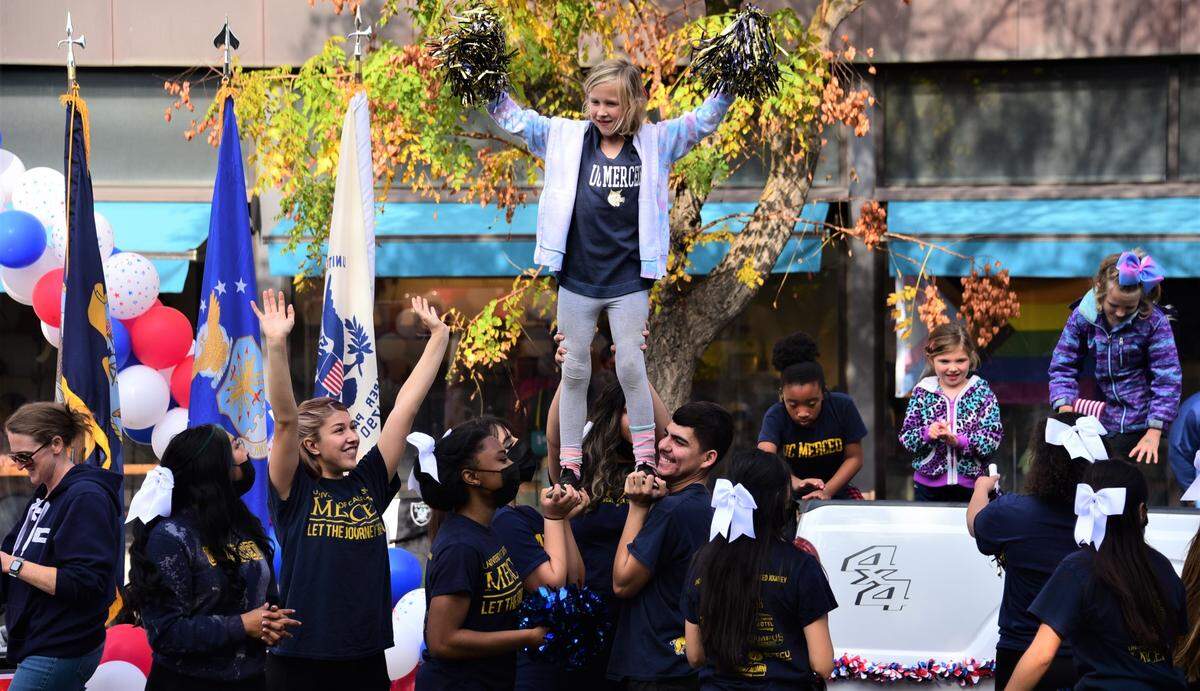 UC Merced cheerleaders hold up a young cheerleader during the Veterans Day Parade on Thursday, Nov. 11, 2021, in downtown Merced, Calif.