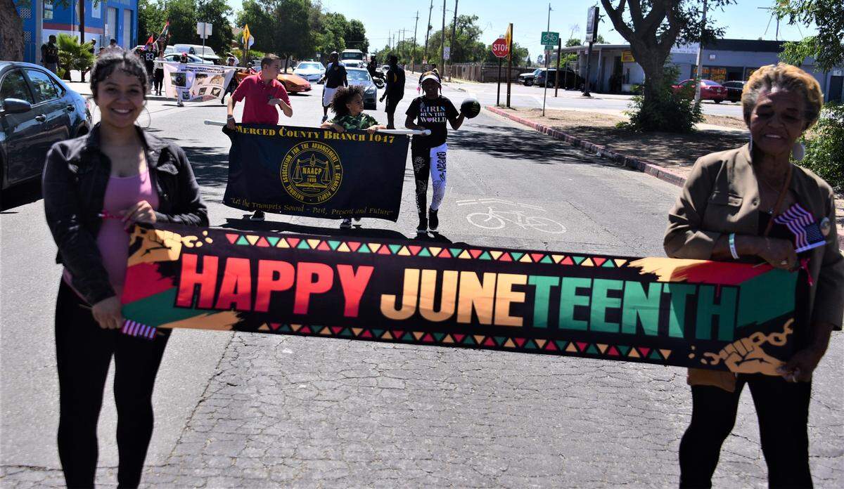 Alyssha Pierce and Diana Pierce hold a Happy Juneteenth banner as they walk during the first Juneteenth Parade in Merced, Calif. on Saturday, June 18, 2022.