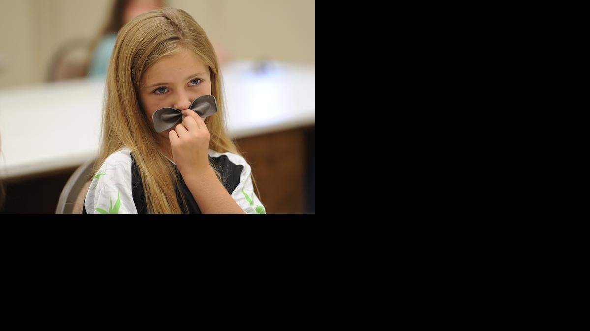  Classes offered in College for Kids include crafts. Kalysta Drake, 10, makes a moustache of a bracelet she made last year.
