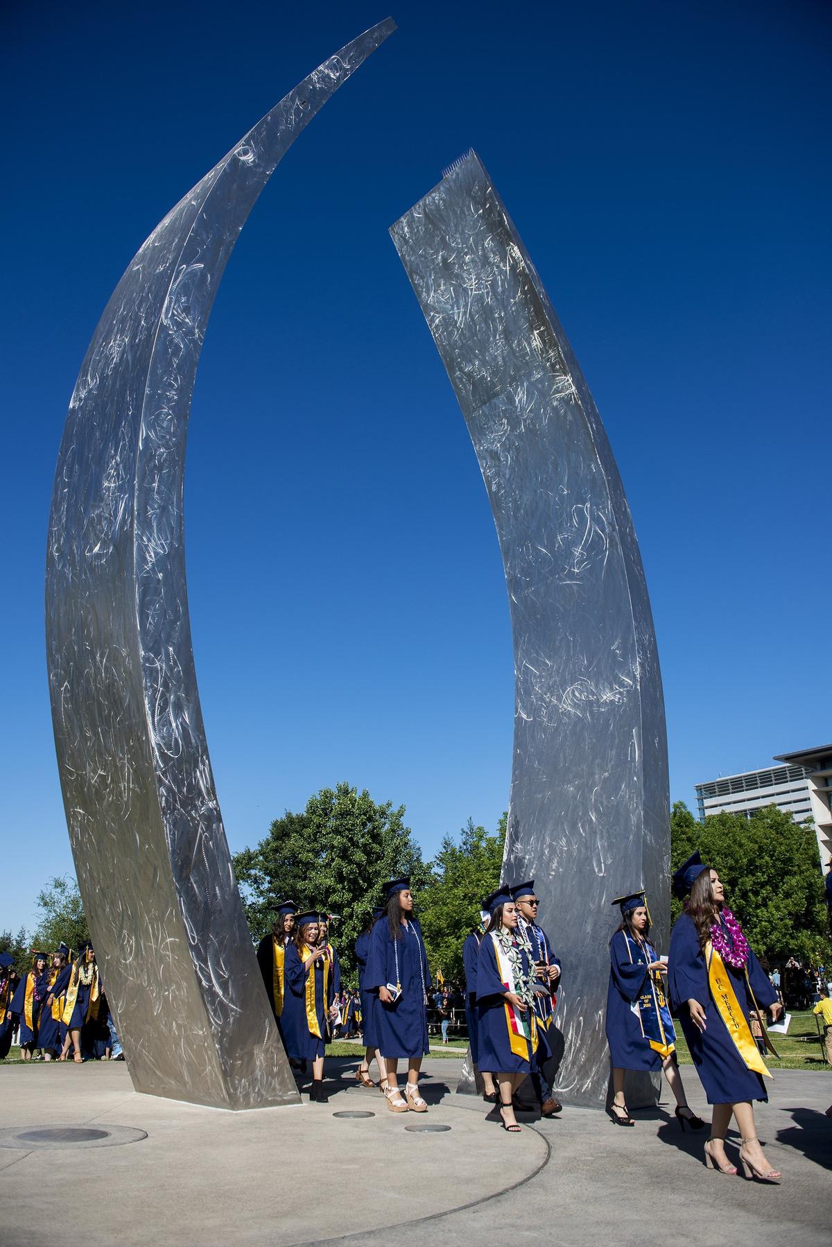 Graduates walk through the “Beginnings” sculpture during the University of California, Merced School of Social Sciences, Humanities and Arts spring commencement in the Carol Tomlinson-Keasey Quad on the UC Merced campus in Merced, Calif., on Saturday, May 12, 2018.