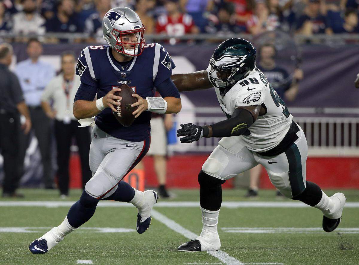 New England Patriots quarterback Danny Etling tries to elude Philadelphia Eagles defensive end Aziz Shittu during the second half of a preseason NFL football game, Thursday, Aug. 16, 2018, in Foxborough, Mass. (AP Photo/Mary Schwalm)