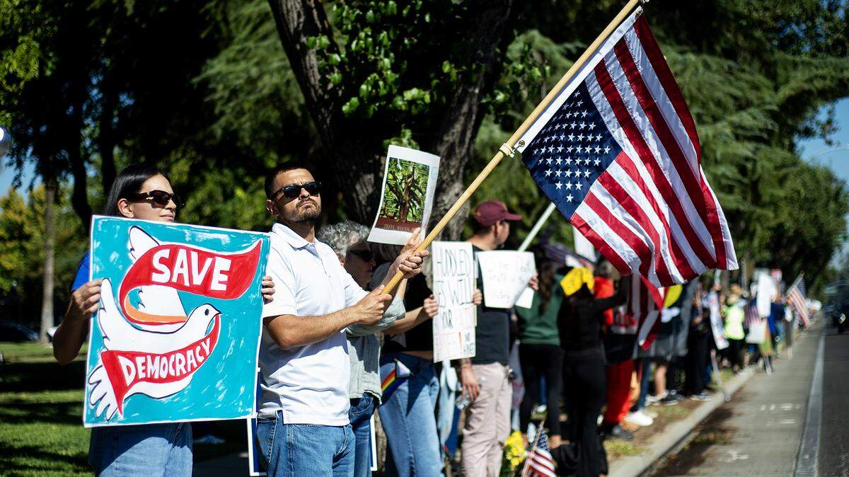 Protesters hold signs and wave flags along M Street during a “No Kings” protest in Merced, Calif., on Saturday, Oct. 18, 2025.