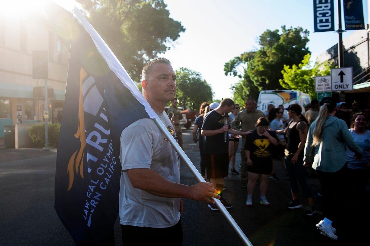 Special Olympics Northern California Regional Director Jeff Godfrey, holds a flag near Bob Hart Square after completing the Law Enforcement Torch Run for Special Olympics Northern California in Merced, Calif., on Thursday, June 15, 2023.