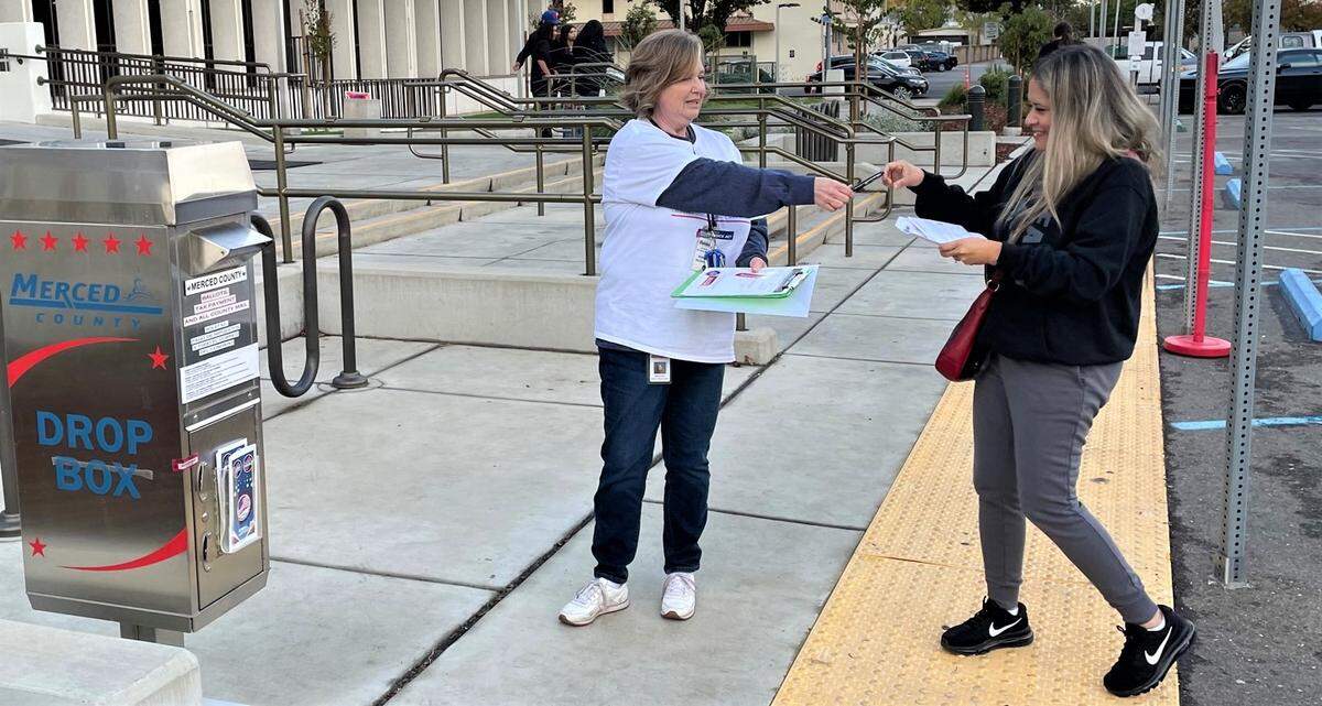 Delniece Davis helps voters turn in their ballot in front of the Merced County Administration Building on Tuesday, Nov. 8, 2022 in Merced, Calif.