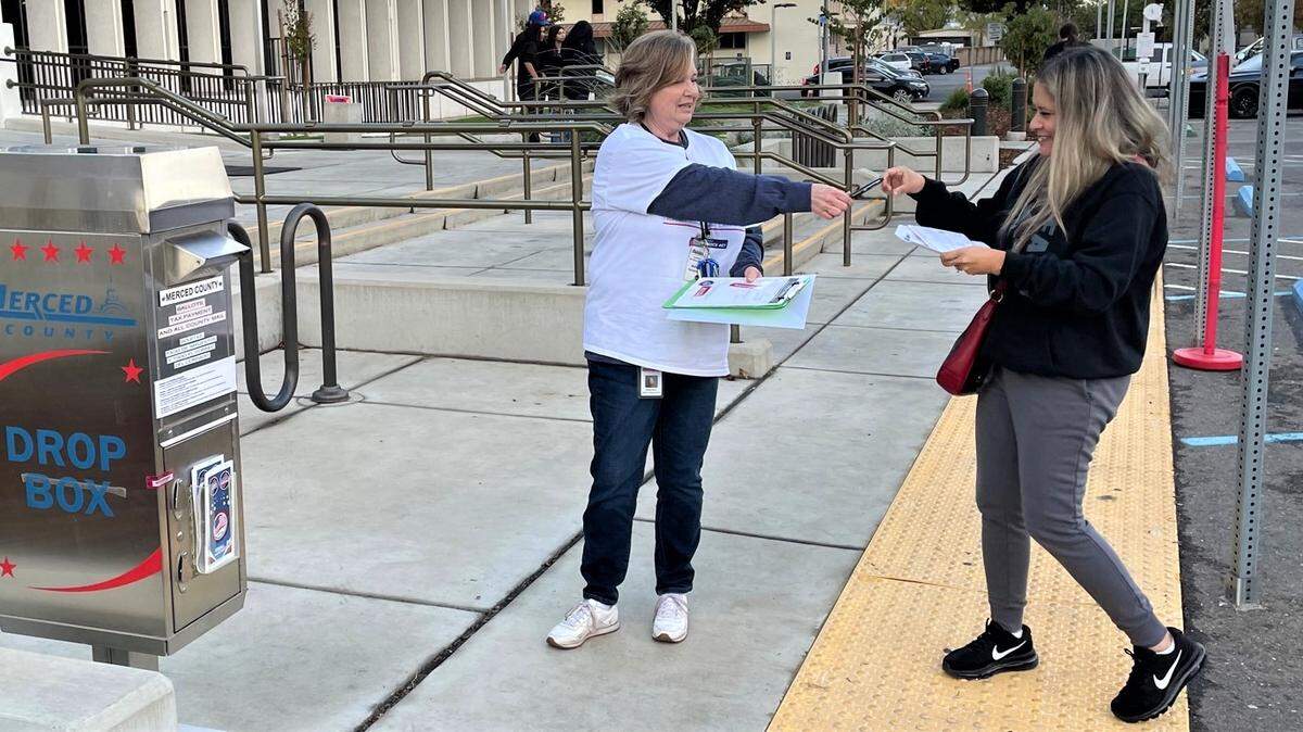Delniece Davis helps voters turn in their ballot in front of the Merced County Administration Building on Tuesday, Nov. 8, 2022 in Merced, Calif.