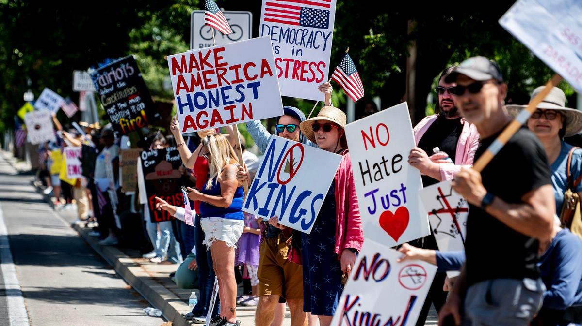 Protesters hold signs along M Street as they take part in a “No Kings” protest in Merced, Calif., on Saturday, June 14, 2025.