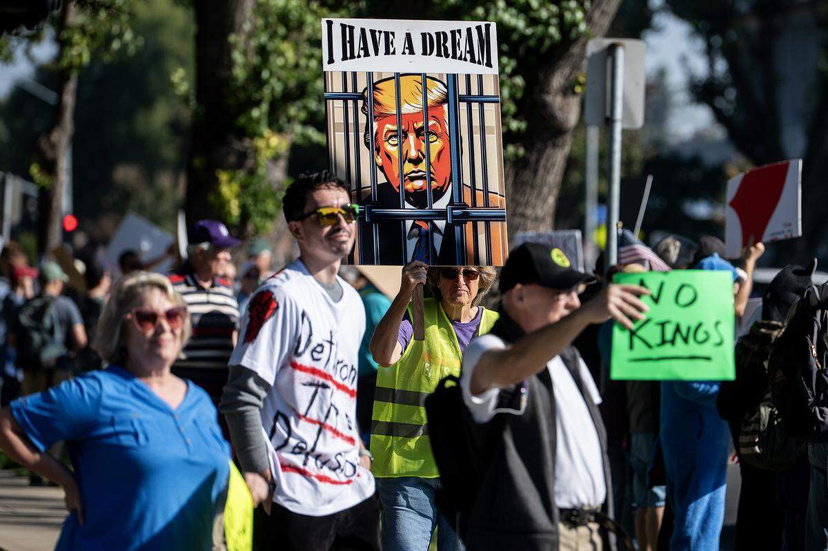 Protesters carry signs while walking along M Street during a “No Kings” protest in Merced, Calif., on Saturday, Oct. 18, 2025. 