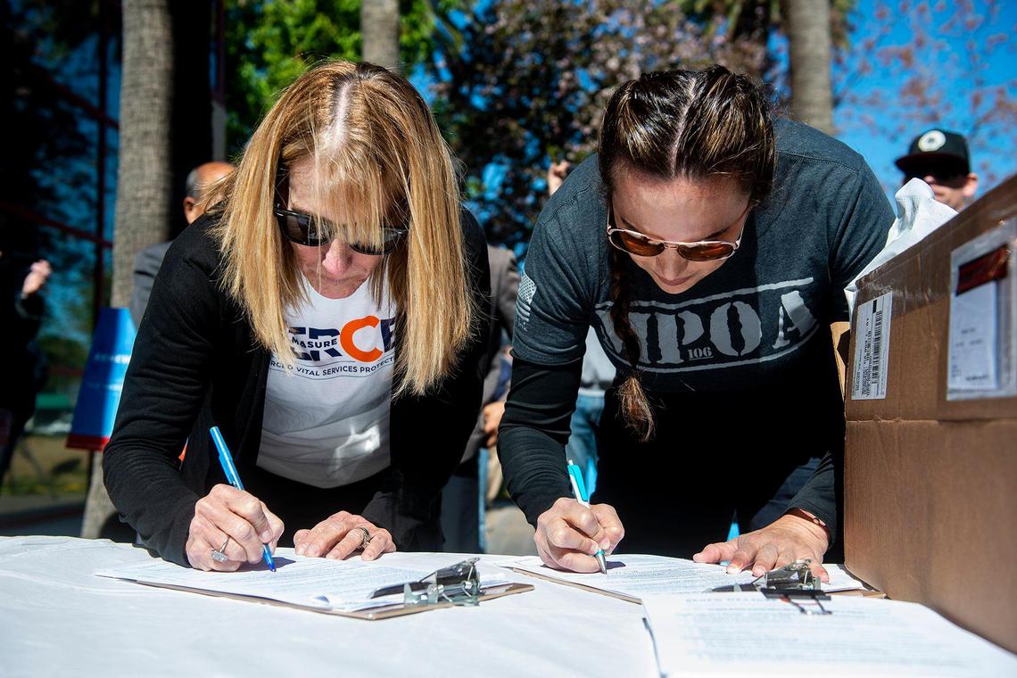 Two Merced residents sign a petition to renew Measure C during a kickoff rally for the petition drive in Merced, Calif., on Thursday, April 13, 2023. The half-cent sales tax was approved in 2006 and funds more than 30 public safety positions as well as providing resources for emergency responses and road improvements. The measure is set to expire in 2026.