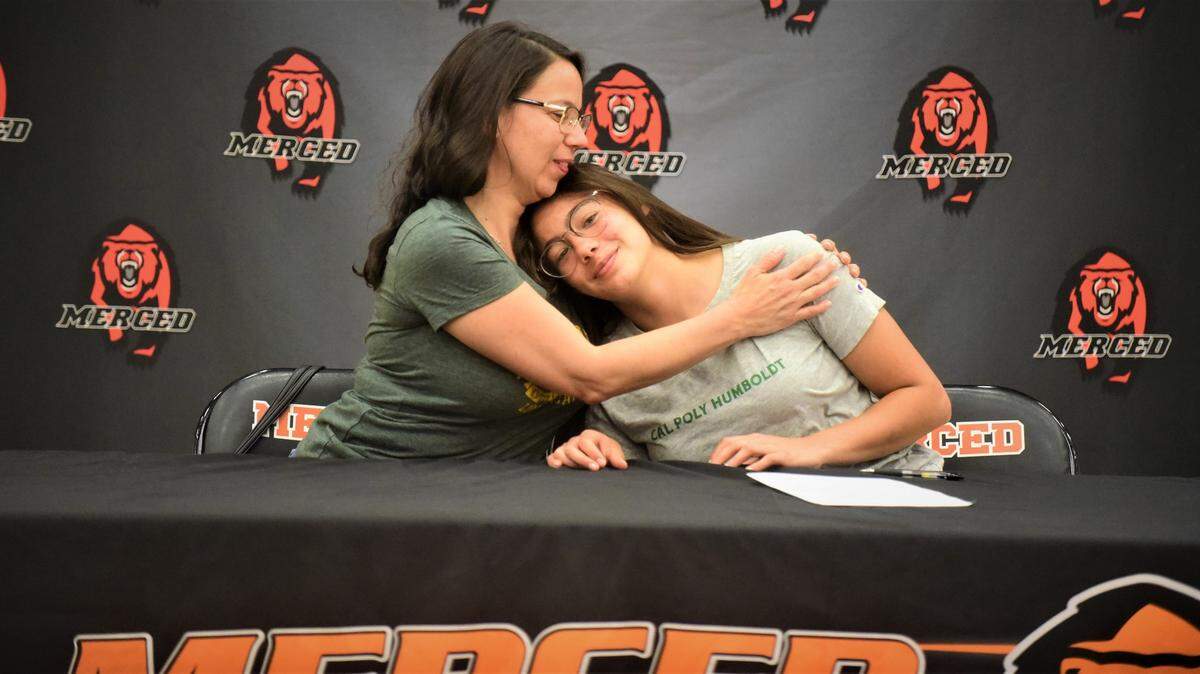 Merced High senior Isabel Perez-Zoghbi is hugged by her mother Maria Zoghbi after she signs her national letter of intent to accept a track & field scholarship to Cal Poly Humbold during a ceremony on Tuesday, May 24, 2022 at the Merced High gymnasium.