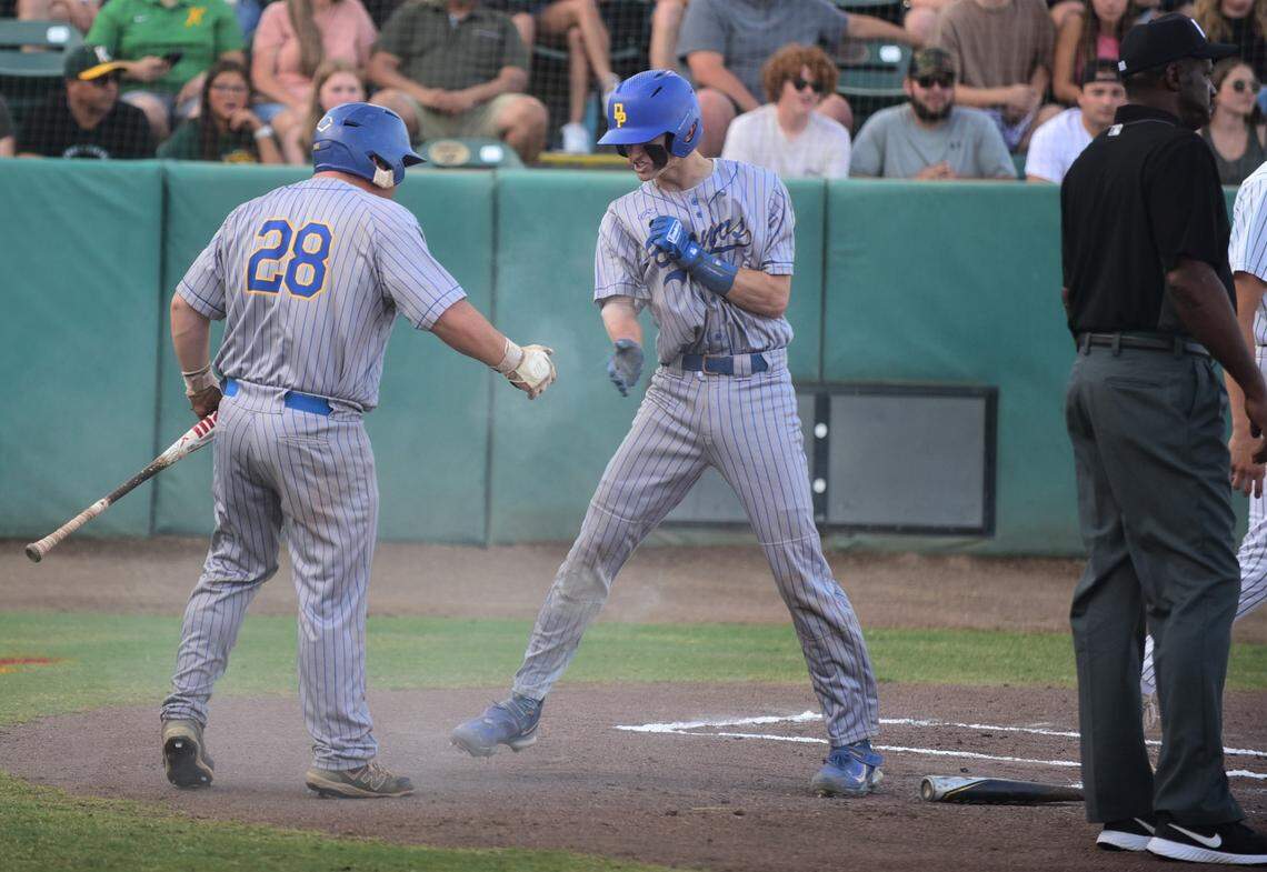 Dos Palos High School junior Peyton Van Worth (5) high-fives teammate Kanoa Ruiz after scoring the first run of the game in the Central Section Division III championship game against Kingsburg on Thursday, May 25, 2023 at Valley Strong Ballpark in Visalia, Calif.