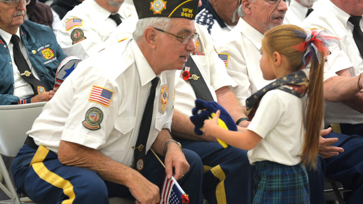 Veteran Rick Toscano talks with a student who presents him with a special pair of slippers during the veterans celebration held at Our Lady Fatima School in Los Banos Friday, Nov. 9, 2018.