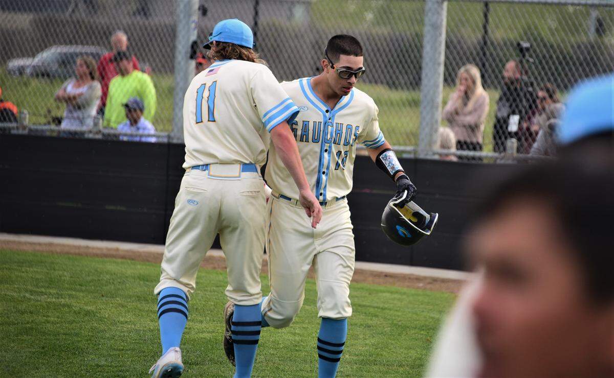 El Capitan High School sophomore Juan Munoz (right) is greeted near the Gauchos dugout after scoring a run in the fourth inning during a 2-0 win over Merced on Wednesday, March 30, 2022 at El Capitan High School.