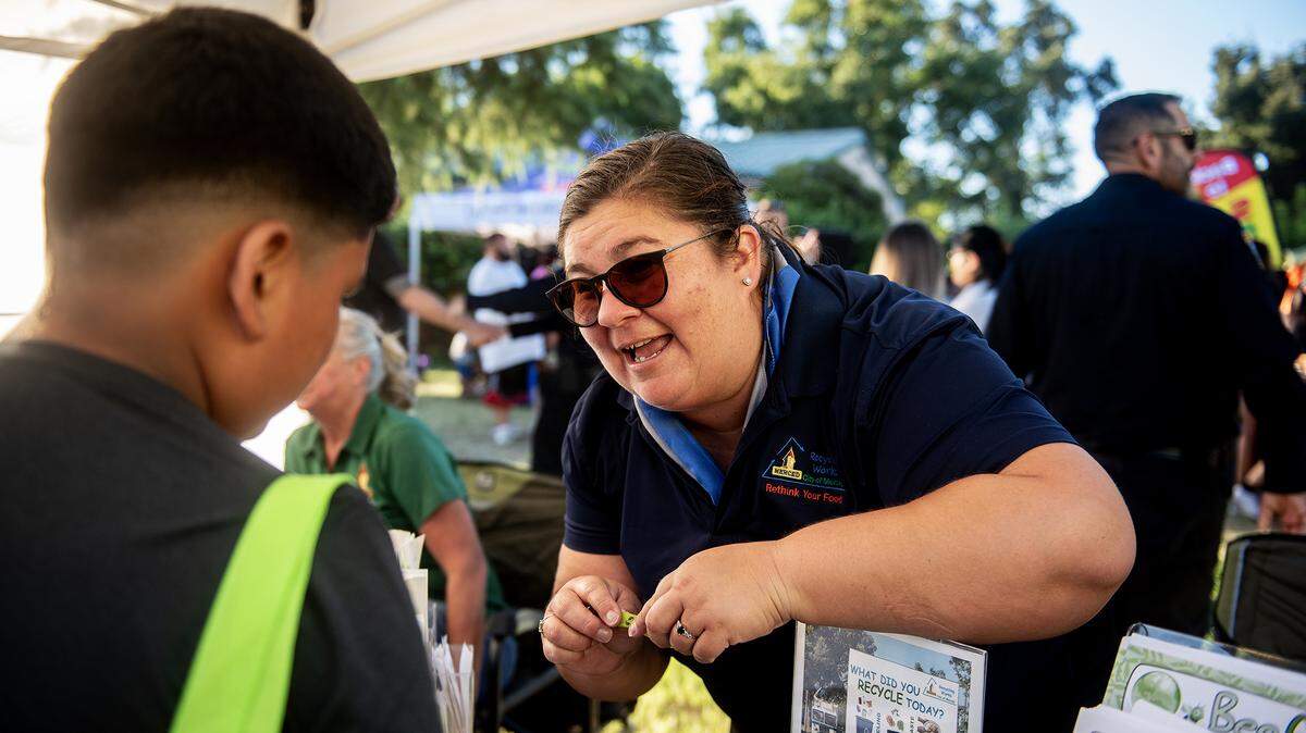 City of Merced Recycling Coordinator Monique Gama, speaks with a child about recycling during the National Night Out event at Applegate Park in Merced, Calif., on Tuesday, Aug. 5, 2025. 