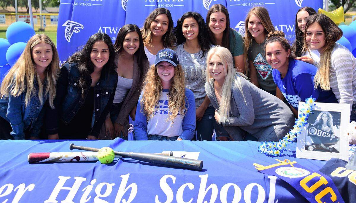 Atwater High senior Megan Escobar (sitting, middle) poses for photos with her softball teammates after signing her national letter of intent to accept a softball scholarship to UC Santa Barbara on Thursday, May 9, 2019 at Atwater High.
