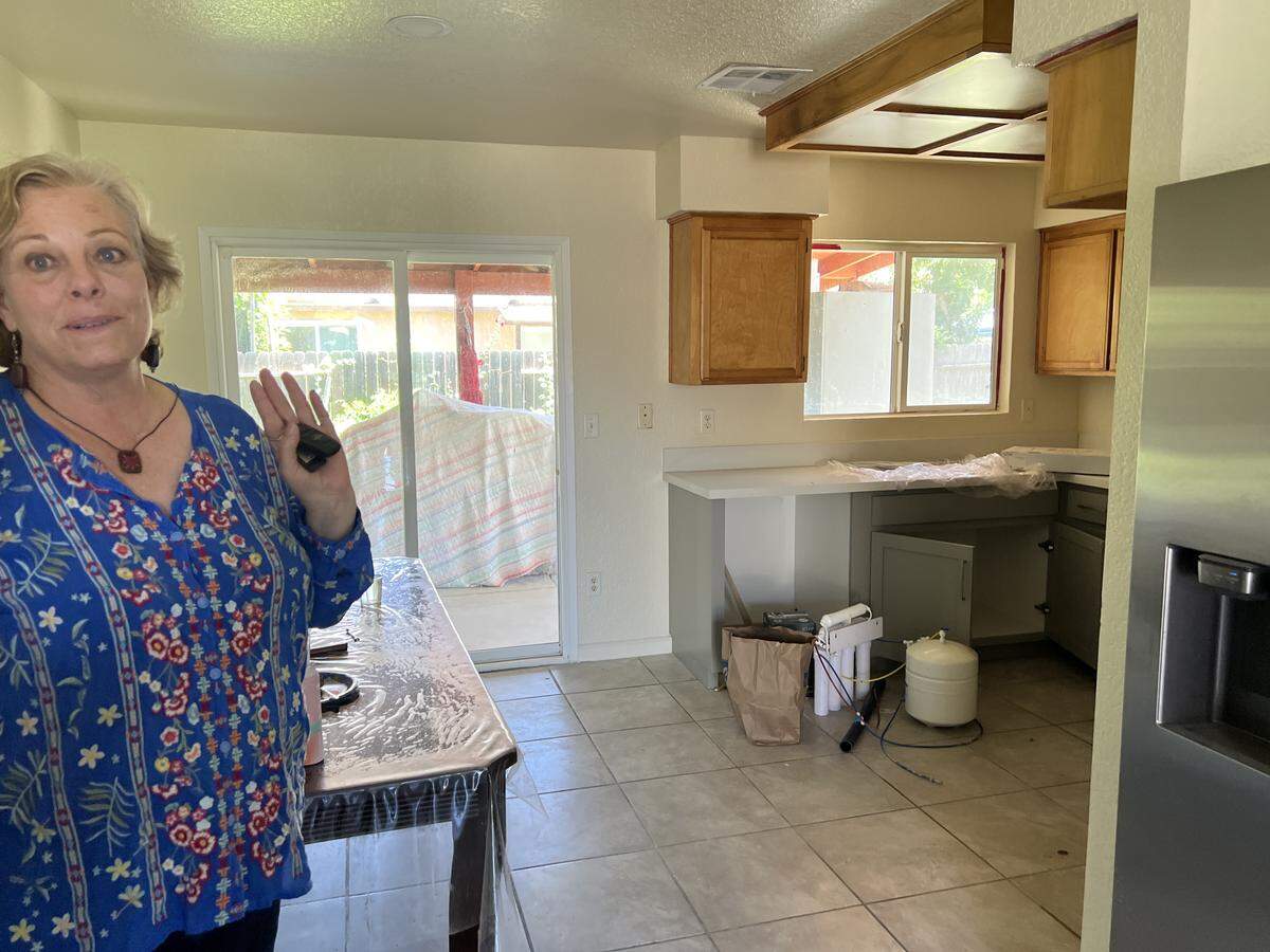A woman stands in a kitchen under construction.