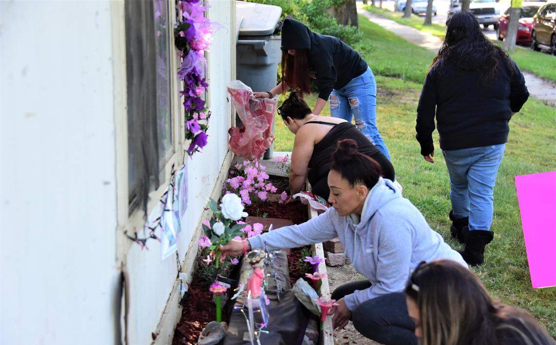 Victoria Lopez, center, helps decorate a flower bed with family and friends in honor of Lopez’s daughter Tatyanna Lopez, who was killed one year ago in Merced.