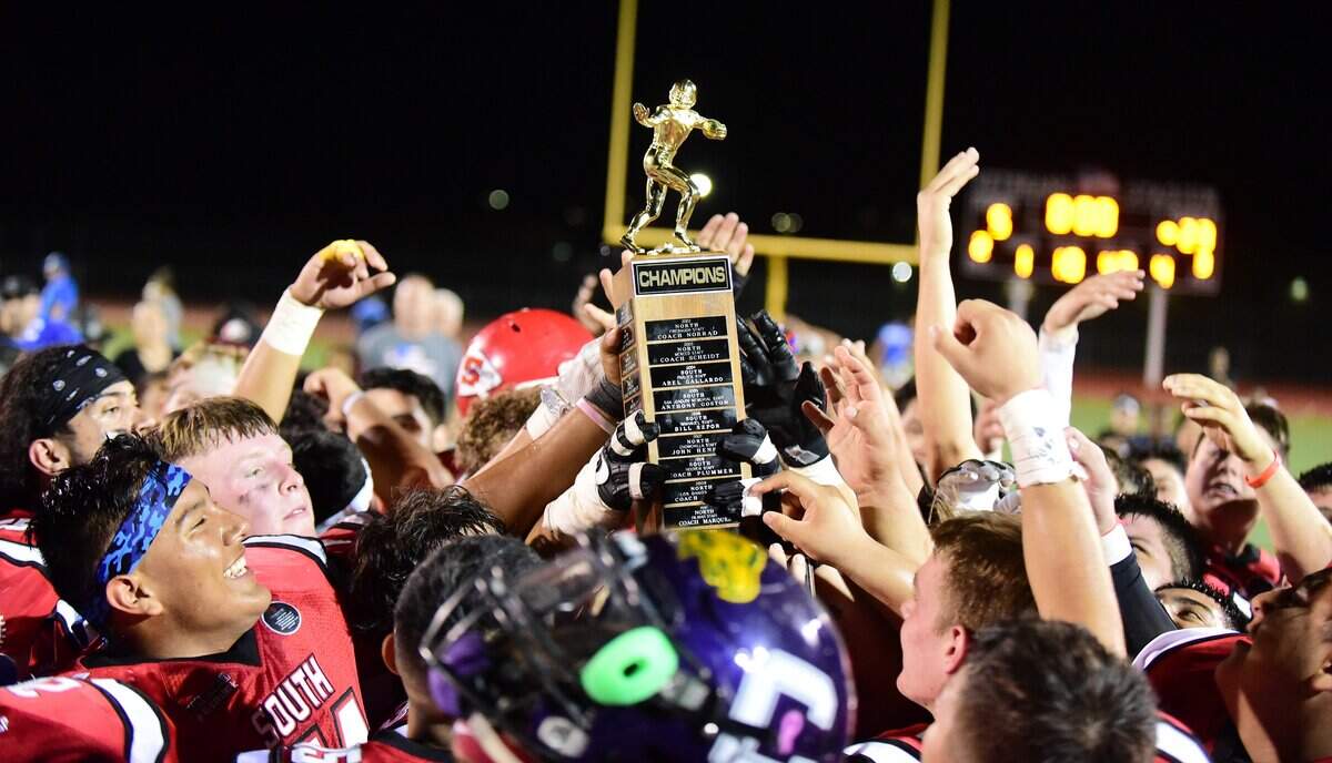 The South celebrates with a trophy after defeating the North 23-5 in the 34th annual North/South Rotary Bob Green Football Classic at Veterans Stadium in Merced, Calif.