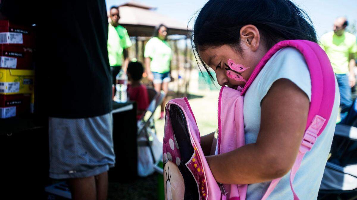 Merced Sun-Star File Image - Kristen Ramirez, 7, of Merced, looks inside her new backpack during a community event which provided backpacks and shoes to area children at McNamara Park in Merced, Calif., Saturday, Aug. 15, 2015. The backpacks were provided by Distinguished Outreach Services and shoes were provided by The TLC Collaborative.