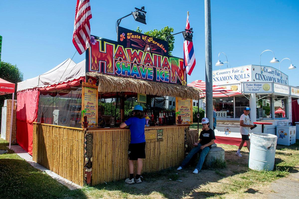 Customers order shave ice from the Hawaiian Shave Ice stand at the Merced County Fair in Merced, Calif., on Thursday, June 6, 2024.