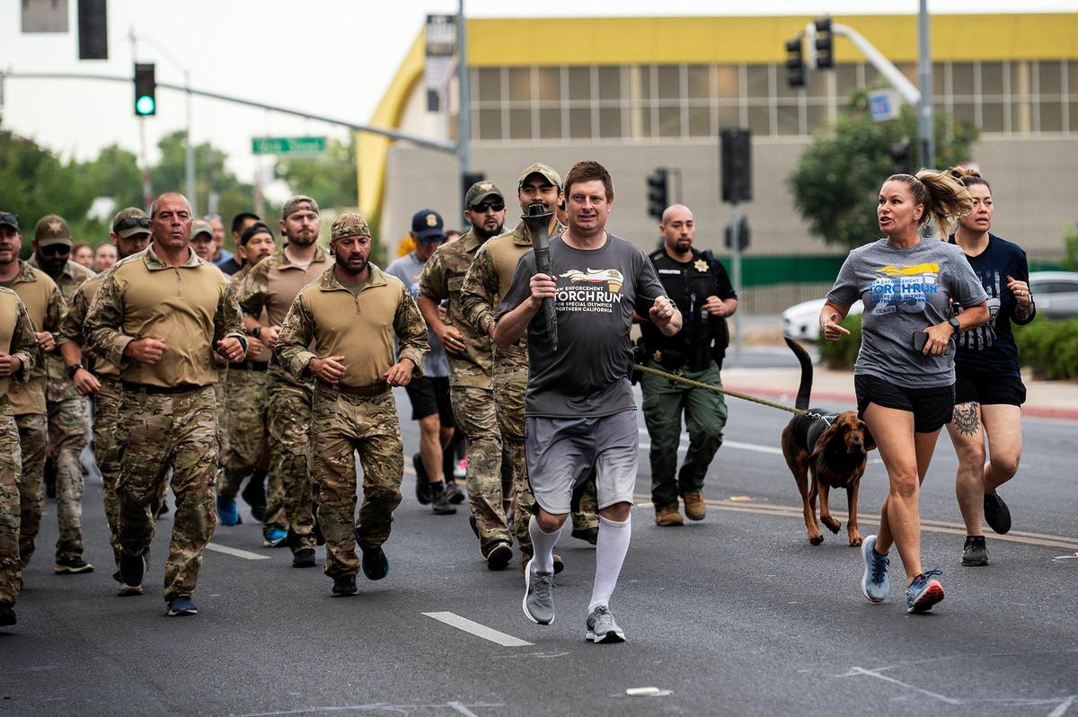 Special Olympics athlete and Merced resident,Mark Heffner, 40, carries the Special Olympics Torch during the Law Enforcement Torch Run for Special Olympics Northern California in Merced, Calif., on Wednesday, June 22, 2022. This year marks the 25th anniversary of the Law Enforcement Torch Run for the Special Olympics Northern California.