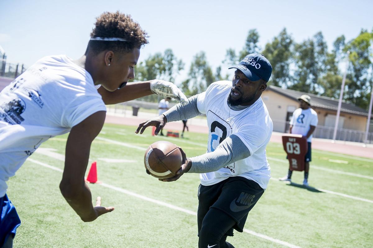 Super Bowl champion and Indianapolis Colts running back Robert Turbin, right, hands the ball off during running back drills at the Achieve Dreams Youth Football Camp at Veterans Stadium on the campus of Golden Valley High School in Merced, Calif., on Saturday, May 12, 2018. The camp is hosted by Golden Valley graduate and Canadian Football League all-star Chris Randle. This is the second year Randle has hosted the camp which is offered free of charge to children ages 6-18.