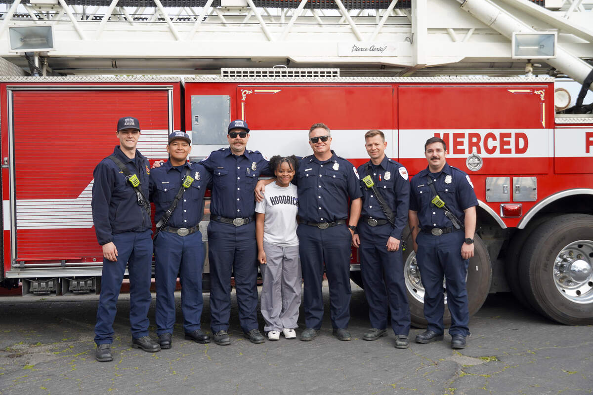 Hoover Middle School student Lailah Brooks, 13, poses for a photo with firefighters from the Merced City Fire Department who made a surprise visit to the school on Friday, March 14, 2025.