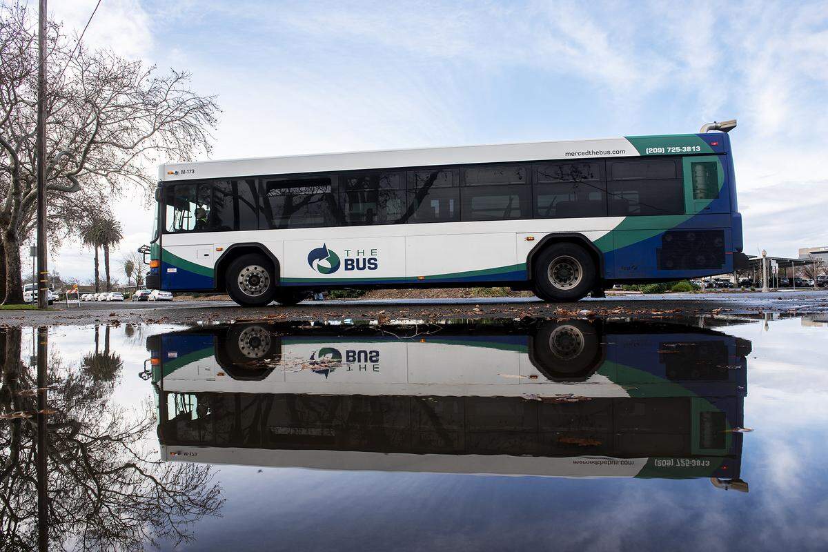 A bus drives past a flooded section of roadway at the intersection of West 23rd and Canal streets in Merced, Calif., on Wednesday, Jan. 4, 2023.