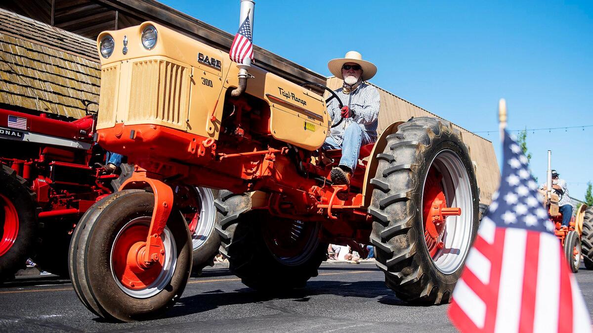 Vintage tractors drive along Broadway Avenue during a Fourth of July parade in Atwater, Calif., on Monday, July 4, 2022.