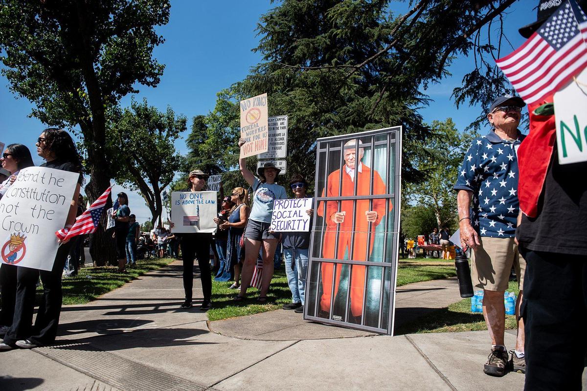 Protesters hold signs next to an image of U.S. President Donald Trump behind bars, as they take part in a “No Kings” protest in Merced, Calif., on Saturday, June 14, 2025.