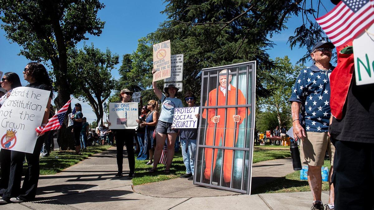 Protesters hold signs next to an image of U.S. President Donald Trump behind bars, as they take part in a “No Kings” protest in Merced, Calif., on Saturday, June 14, 2025.