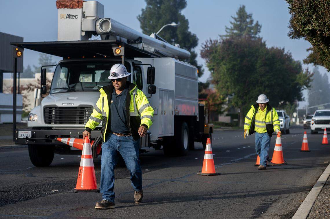 City of Merced Arborist and Public Works Director for Parks and Trees Division, Angel Nunez, 46, places cones in the roadway as crews work to remove selected trees from the median along West Olive Avenue in Merced, Calif., on Thursday, Nov. 6, 2025. 