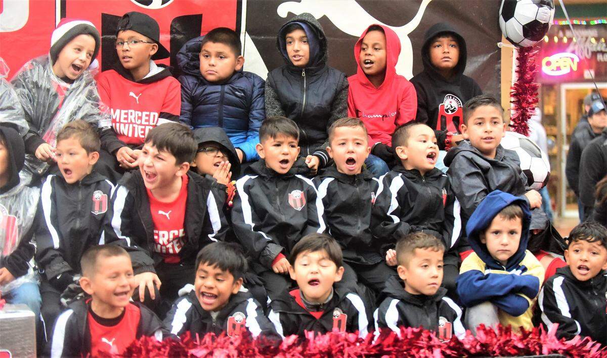 Members of Merced United youth soccer organization sit atop a float as they make their way down Main Street during the Merced Christmas Parade on Saturday, Dec. 3, 2022.