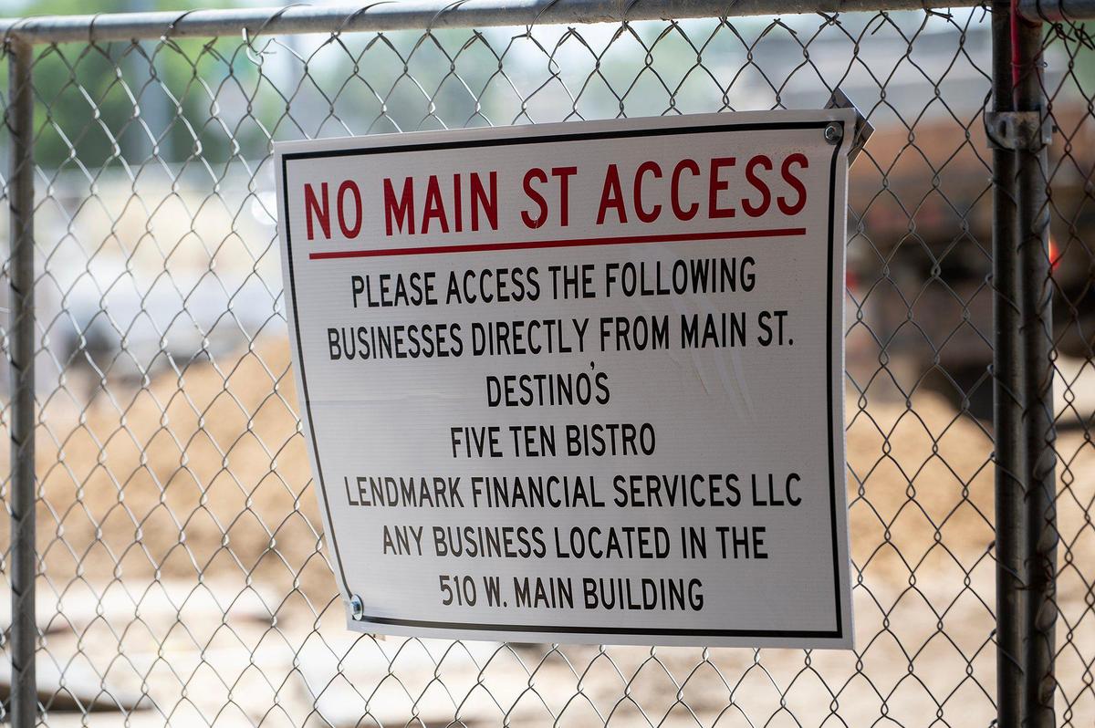 A sign indicating access to nearby businesses hangs a fence as construction continues at Bob Hart Square in Merced, Calif., on Friday, May 16, 2025. According to the City of Merced, the renovation to the square will include an extended plaza-like design, the addition of trees, a seating area and a stage.