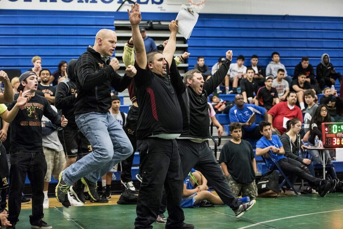 Golden Valley coach Chopper Mello (right) celebrates a victory for one of his wrestlers during the 2016 Central California Conference Championships at Atwater High. Mello recently picked up career CCC win No. 100 as coach of the Cougars.