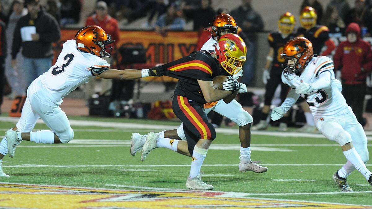 Oakdale running back, Leo Ayala, center is grabbed from behind by Merced defensive back, Quincey Collins in the fourth quarter Friday night, Nov. 22, 2019 in Oakdale.