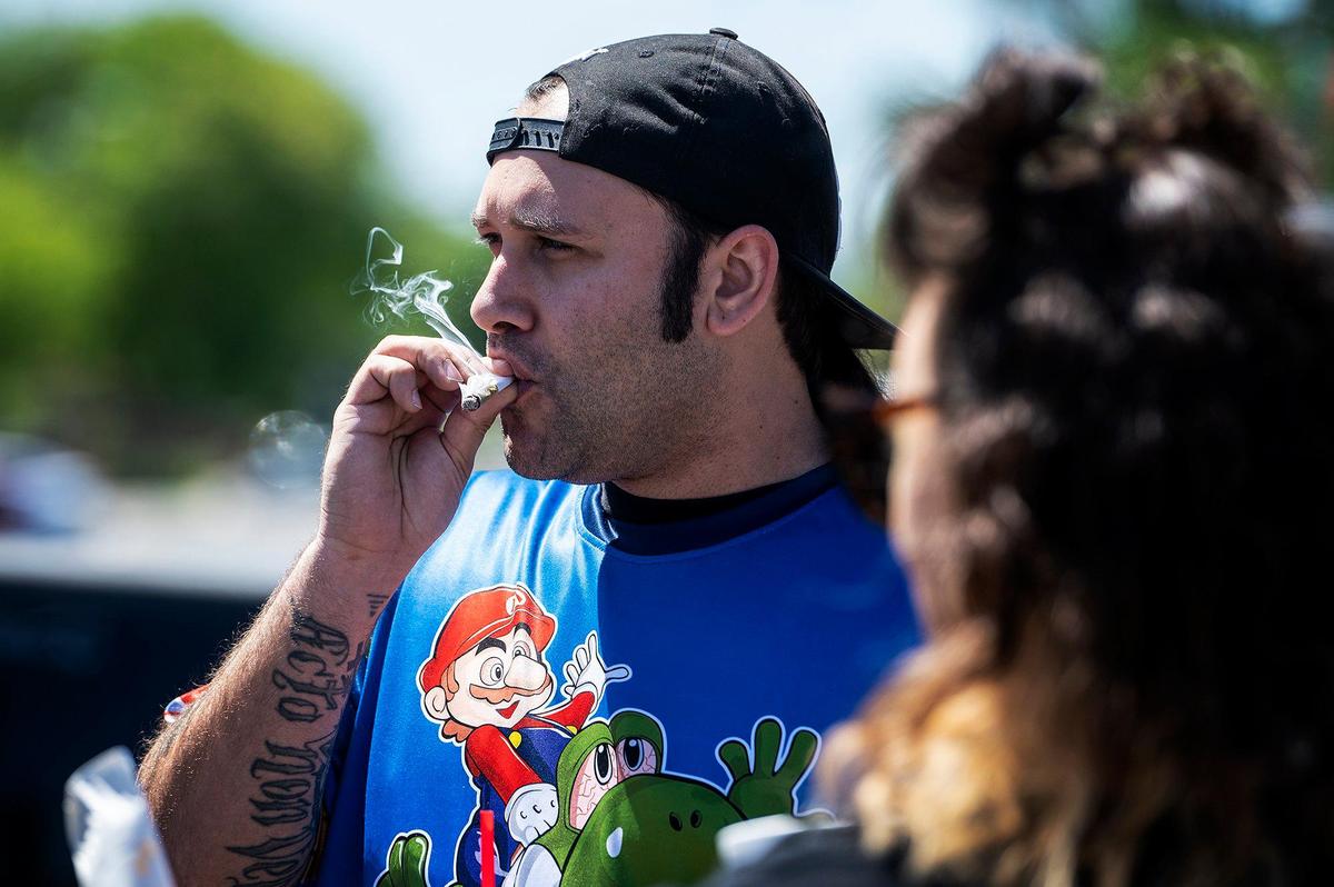 Chad Moore, 31, of Gustine, smokes a joint with friends during a 420 celebration on Third Avenue in Gustine, Calif., on Wednesday, April 20, 2022. The event included smoke shop items for sale, food vendors and live music.