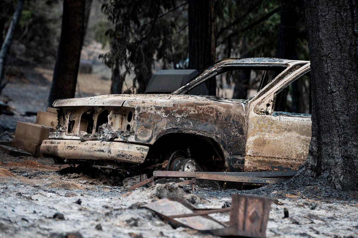 A charred vehicle sits on a property along Jerseydale Road as firefighters continue to battle the Oak Fire in Mariposa County, Calif., on Tuesday, July 26, 2022.