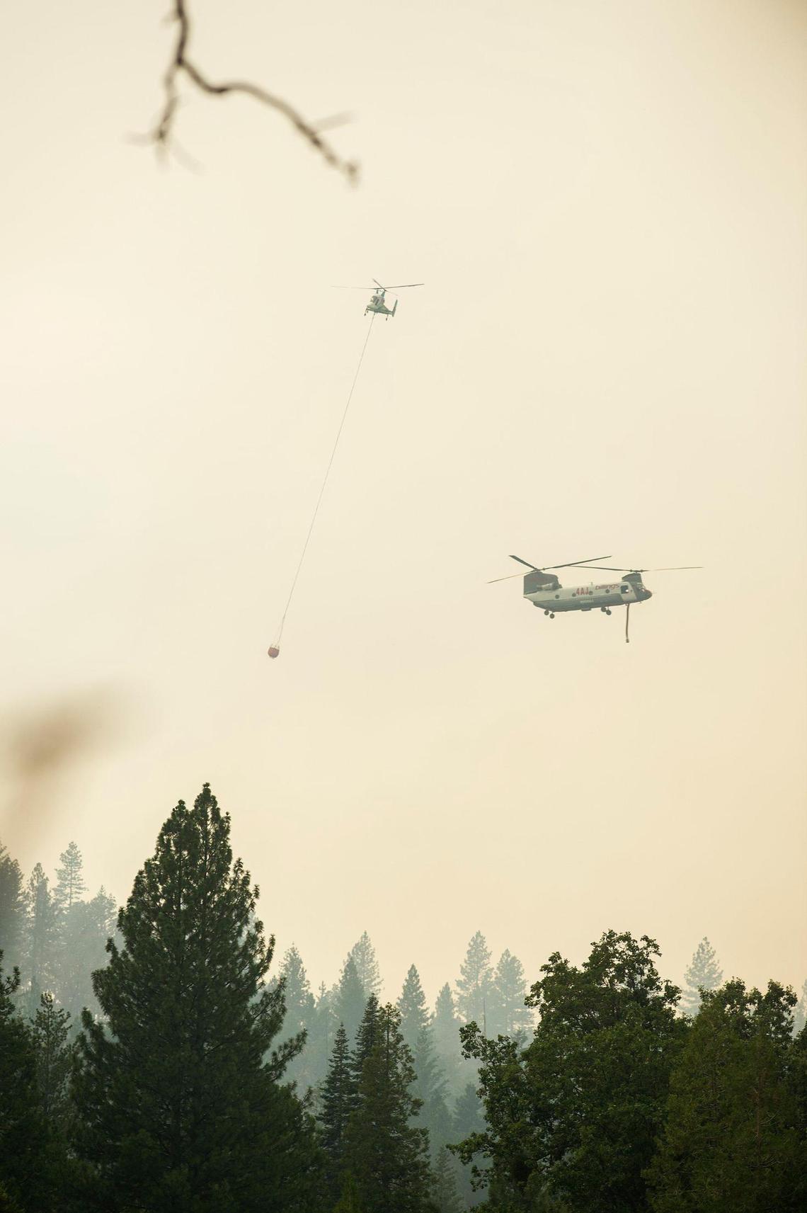 Firefighting helicopters pass each other west of Scott Road as firefighters continue to battle the Oak Fire in Mariposa County, Calif., on Tuesday, July 26, 2022.