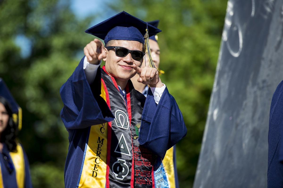 A graduate points to people in the crowd during the University of California, Merced School of Social Sciences, Humanities and Arts spring commencement in the Carol Tomlinson-Keasey Quad on the UC Merced campus in Merced, Calif., on Saturday, May 12, 2018.