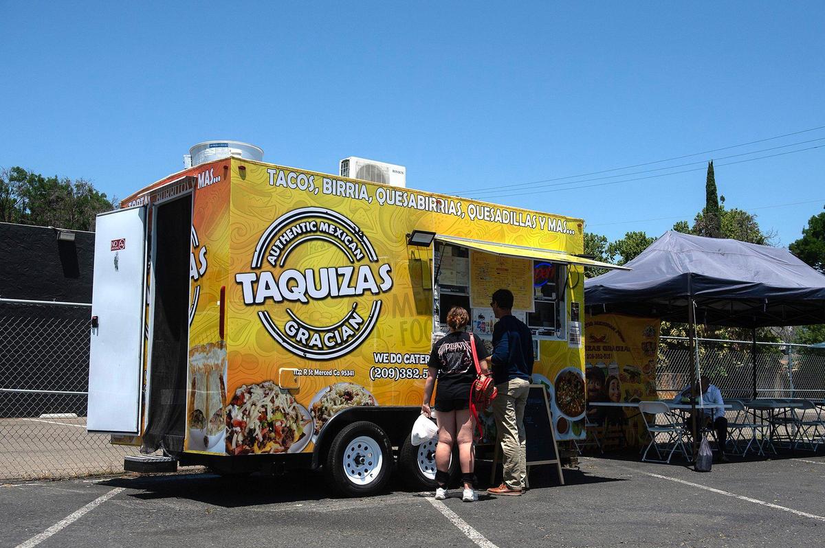 Customers pick up an order from Taquizas Gracian food truck, located at 825 West Main Street in Merced, Calif., on Tuesday, June 10, 2025.