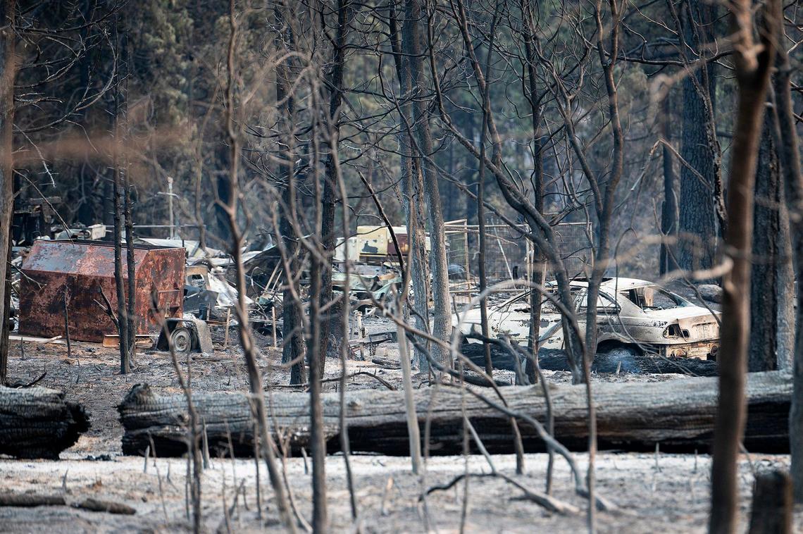 A charred vehicle and items sit on a property along Wild Dove Lane as firefighters continue to battle the Oak Fire in Mariposa County, Calif., on Tuesday, July 26, 2022.
