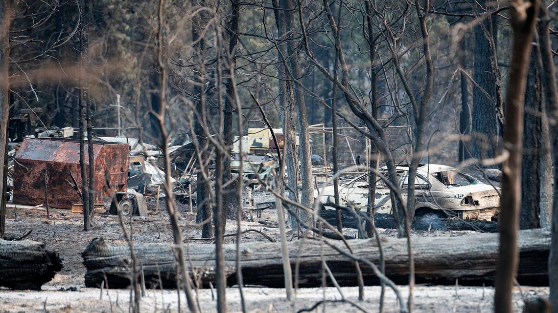A charred vehicle and items sit on a property along Wild Dove Lane as firefighters continue to battle the Oak Fire in Mariposa County, Calif., on Tuesday, July 26, 2022.