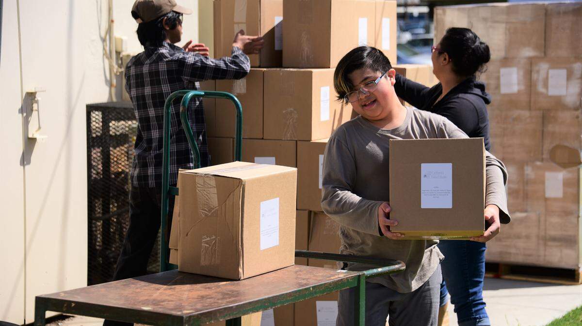 Volunteer R.J. Lopez helps load a cart with boxes of food at the Salvation Army in Merced, Calif. on Friday, March 27, 2020.