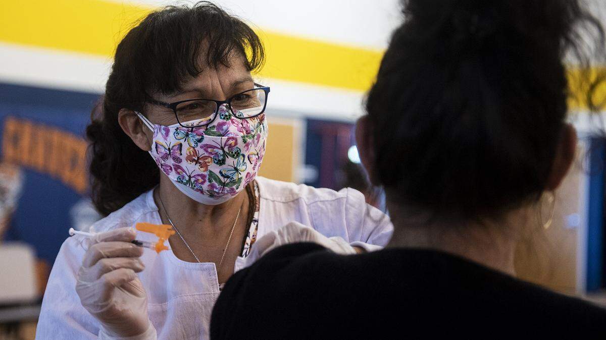 Registered nurse Maria Contreras administers a COVID-19 vaccine to a patient at a vaccination clinic inside the Cesar E. Chavez Middle School gymnasium in Planada, Calif., on Thursday, March 4, 2021.