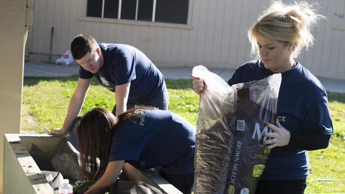 UC Merced Police Sgt. Kari Gomes prepares to spread soil among freshly planted flowers at the local elementary school.