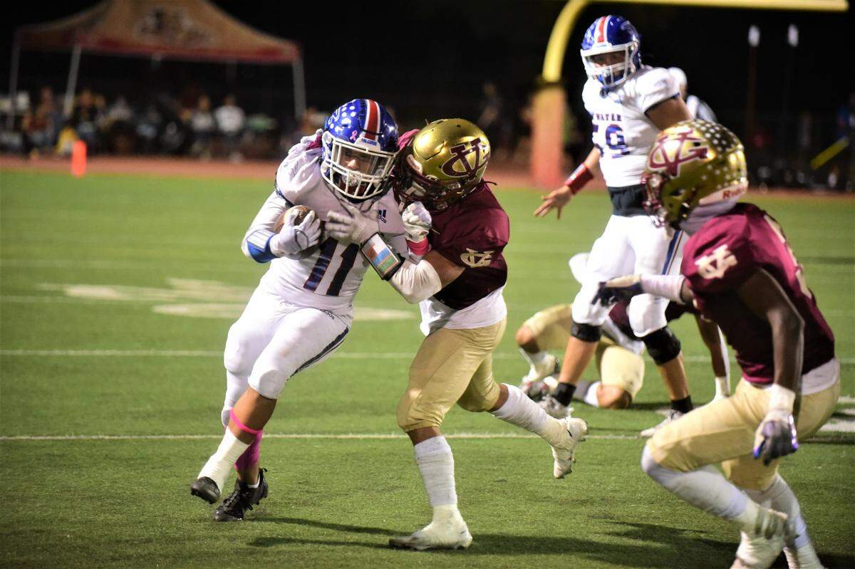 Atwater High running back Josue Garcia (11) runs the ball as Golden Valley’s Ethain Vang attempts to bring him down during a game on Friday, Oct. 7, 2022.
