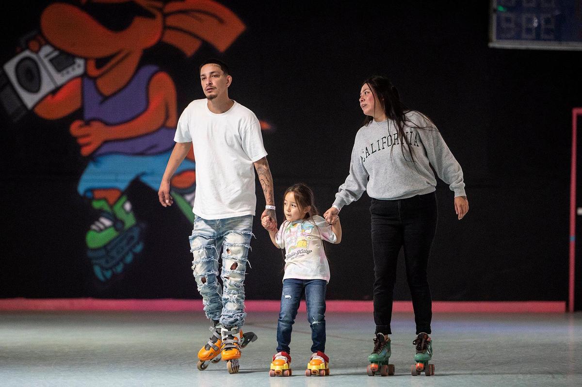 Dillon Vaughan, 28, of San Diego, left, daughter Maleni, 5, center, and Cynthia Perez, 28, of Merced, right, skate around the rink at Roll-er Land in Merced, Calif., on Sunday, Oct. 27, 2024
