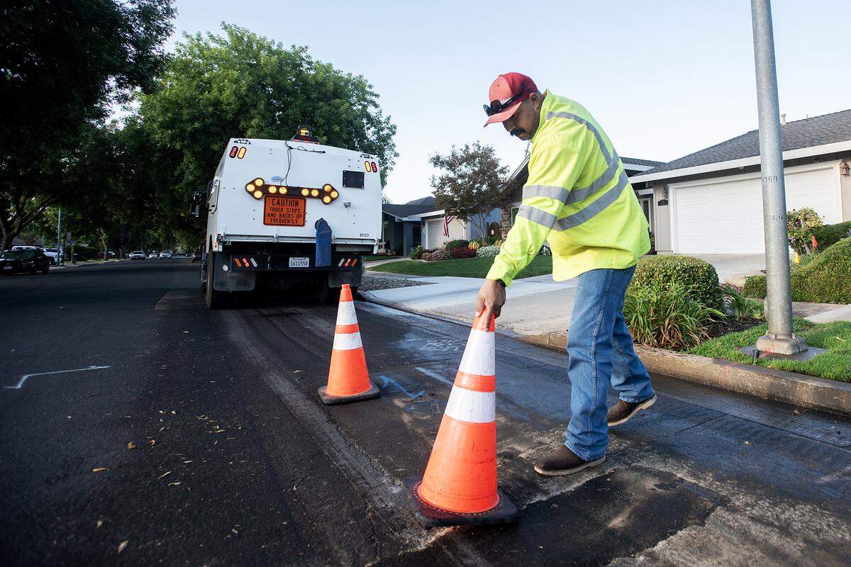 José López, 34, reemplaza un cono mientras barre las calles de un vecindario en Merced, Calif., el jueves 11 de septiembre de 2025. Al haber desarrollado desde niño una fascinación por los camiones y la maquinaria, Lopez dijo que está viviendo su sueño conduciendo y operando los diversos camiones y equipos de la ciudad. 