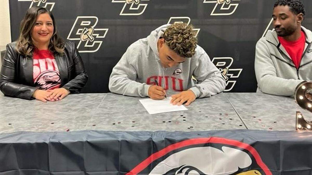 Buhach Colony High School senior Jaxson Percoats (center) signs his national letter of intent to accept a football scholarship to Southern Utah University as his parents Araceli Ochoa and Imani Percoats look on during a signing ceremony at Buhach Colony on Wednesday, Dec. 21, 2022.