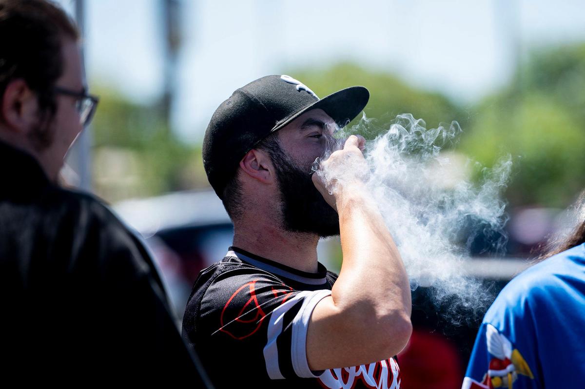 James Riley, 30, of Gustine, smokes a joint with friends during a 420 celebration on Third Avenue in Gustine, Calif., on Wednesday, April 20, 2022. The event included smoke shop items for sale, food vendors and live music.